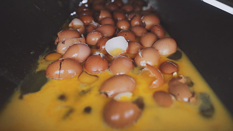 A bunch of eggs in a supply chain, cracked and put into waste